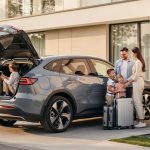 Quelles sont les meilleures voitures électriques pour un usage quotidien ? Une famille charge des bagages dans un SUV électrique moderne devant une maison équipée d’une borne de recharge.