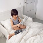 child_boy_lies_in_a_white_children_s_bed_with_a_blanket_in_a