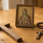 Symboles chrétiens : signification et repères pour le quotidien Composition sobre d’une croix, d’un chapelet et d’une icône chrétienne posés sur une table en bois clair baignée d’une lumière chaleureuse.